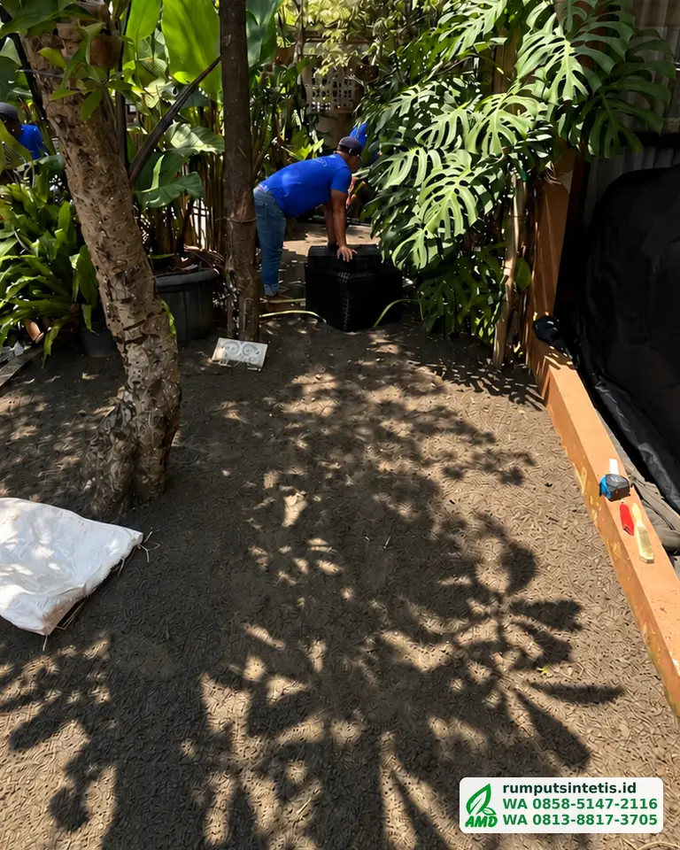 Alas pasir di samping rumah diratakan sebelum rumput sintetis digelar