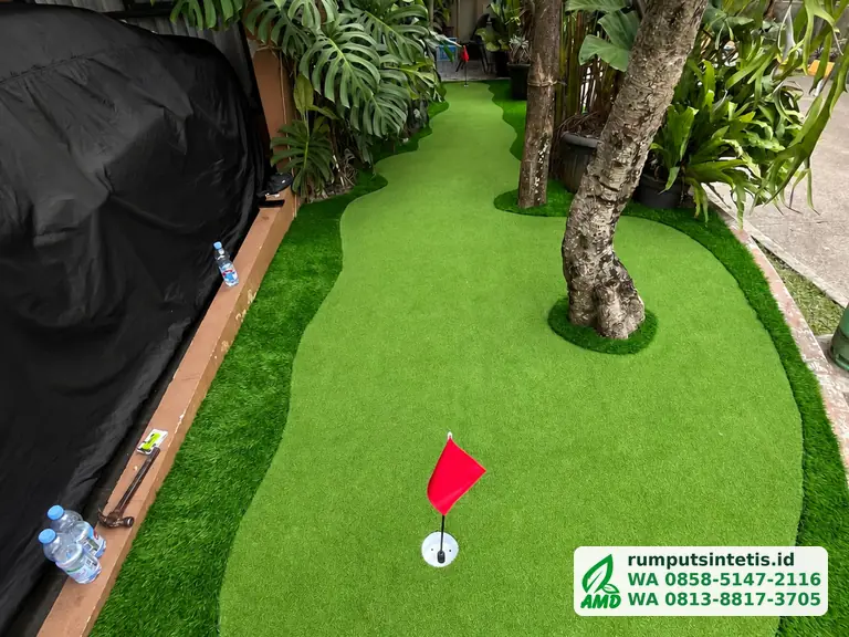 Putting green rumput sintetis di halaman rumah dengan bendera golf