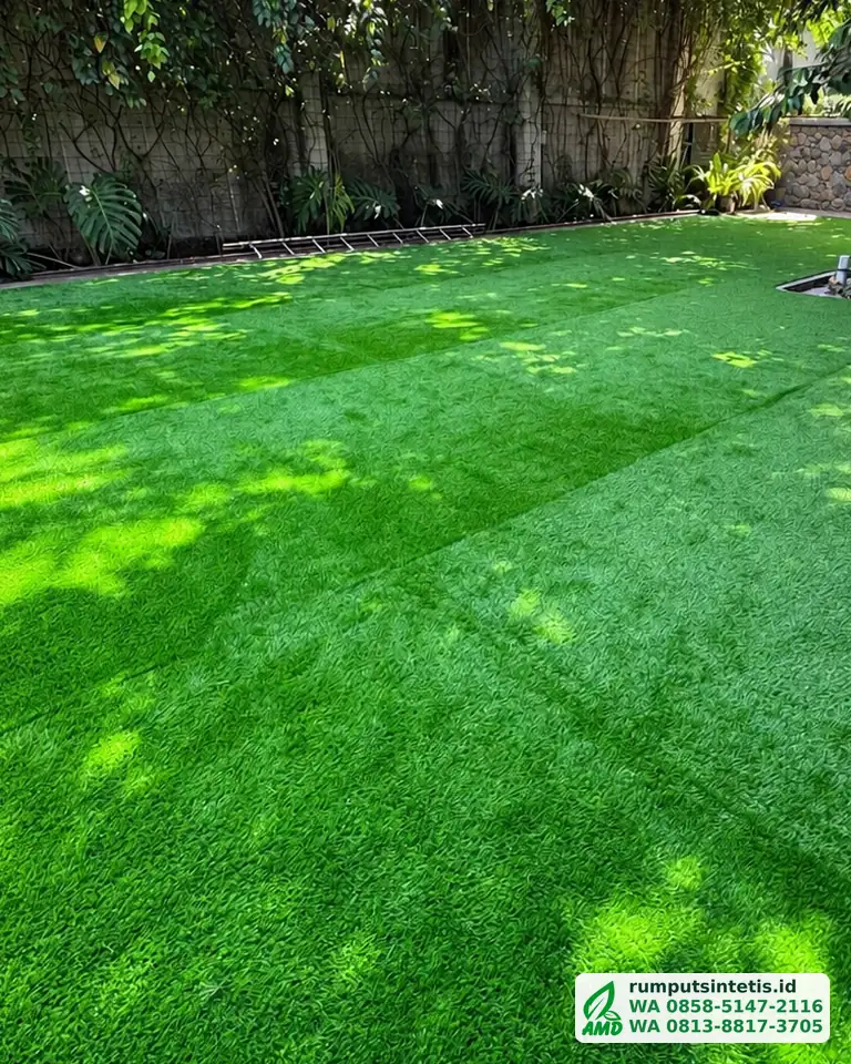 Taman rumput sintetis hijau rata di bawah pohon