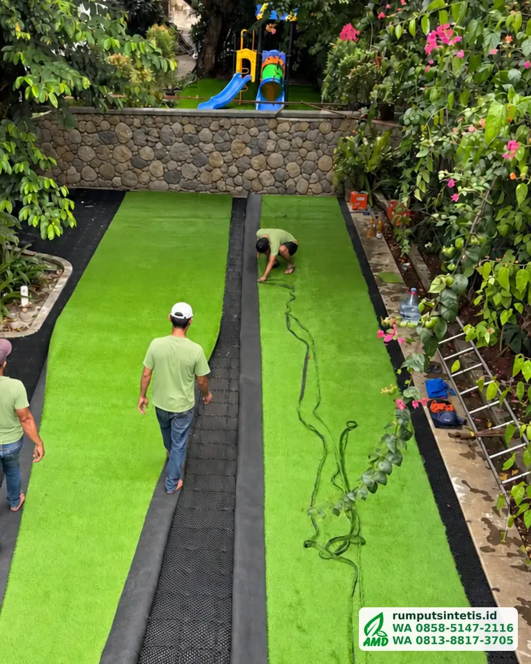 Tim menggelar roll rumput sintetis di atas drainage cell