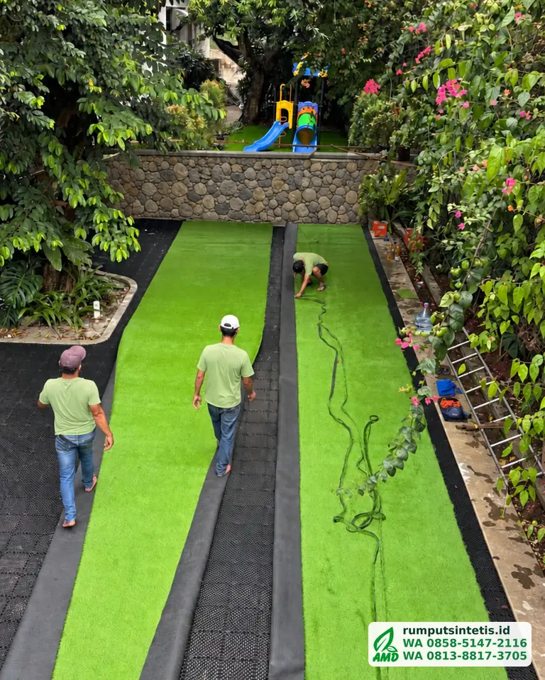 Tim menggelar roll rumput sintetis di atas drainage cell